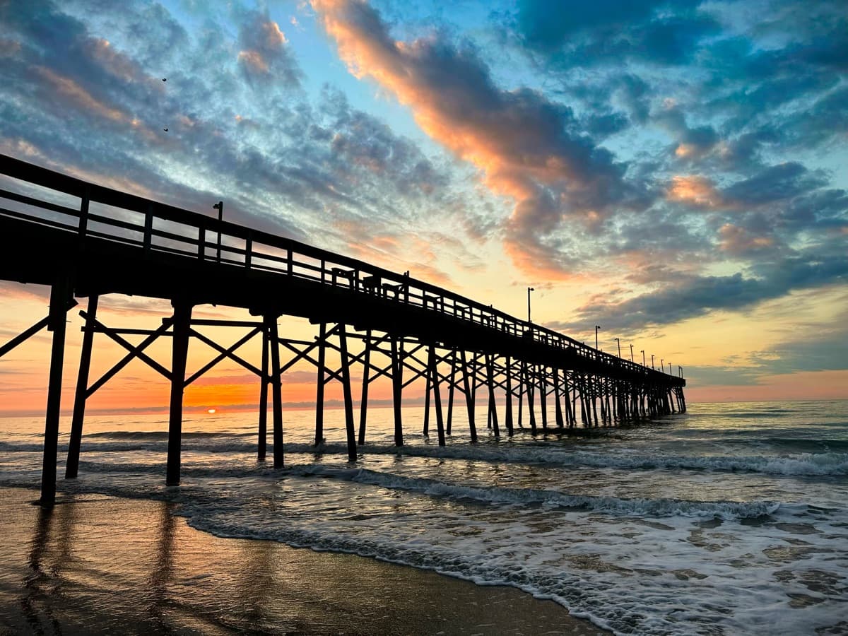 OIB Pier silhouette under dramatic sunset clouds