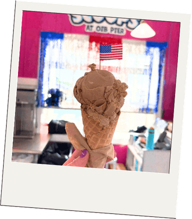 A chocolate scoop cone in front of the Scoops sign